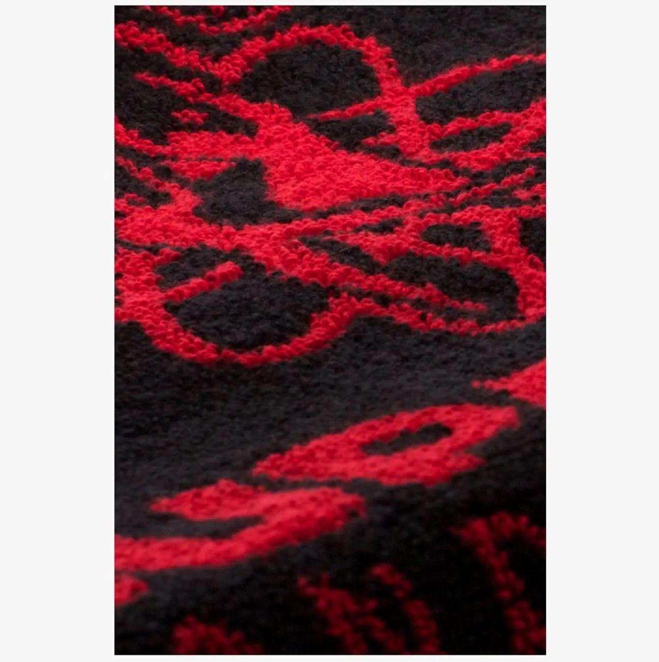 Close-up of Supadance black and red cotton towel showcasing intricate red woven design and plush fabric texture for comfort and durability.