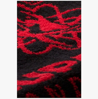 Close-up of Supadance black and red cotton towel showcasing intricate red woven design and plush fabric texture for comfort and durability.